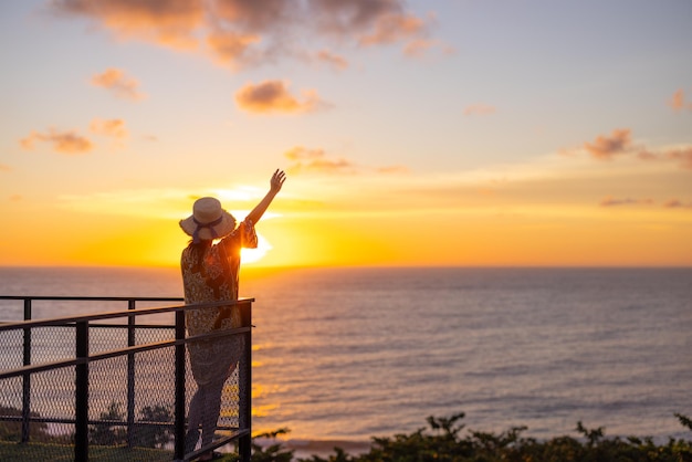 Touristenfrau beobachtet den Sonnenuntergang mit Blick auf das Meer