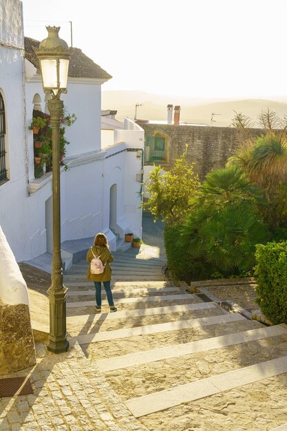 Touristenfrau, die bei Sonnenuntergang an einem sonnigen Tag in der Stadt Medina Sidonia Cadiz durch eine schmale Gasse schlendert