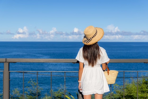 Touristenfrau mit weißem Kleid und Blick auf das Meer im Sommer