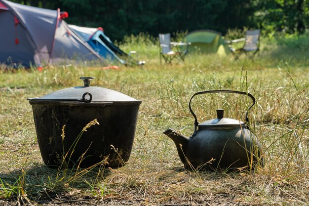 Touristenlager Ein Wasserkocher und ein Kochtopf für Touristen Campingzelte und Klappstühle im Hintergrund
