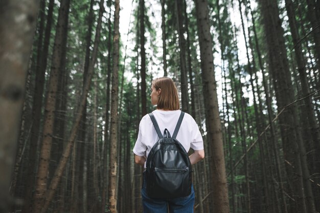 Touristenmädchen, das unter den Tannenbäumen auf dem Wald steht