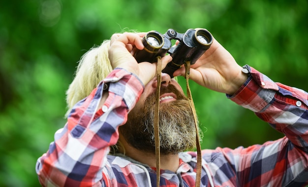 Touristenmann mit Fernglas Auf der Suche nach etwas entlang des Waldes. Mann mit Fernglas-Teleskop im Wald. Reisekonzept. in die Zukunft schauen. Hobby und Entspannung.