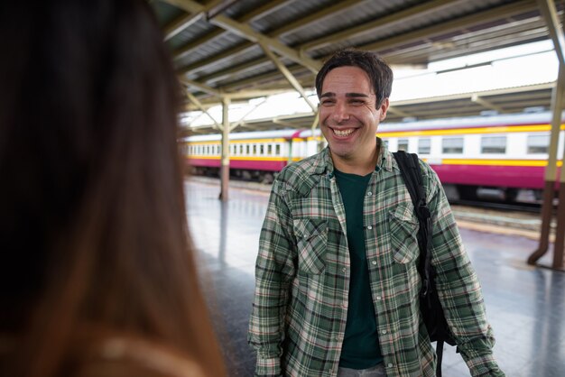 Touristenmann und junge asiatische Touristenfrau zusammen am Bahnhof