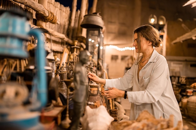 Touristin, die auf dem arabischen Markt in der Nähe von Al Seef mit Geschirrlampen und Laternen im alten Stil spazieren geht