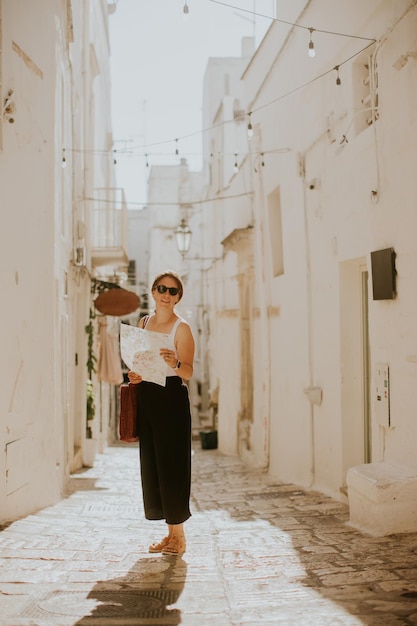 Touristin mit einem Stadtplan aus Papier in den engen Gassen von Ostuni, Italien