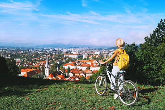 Touristin mit Panoramablick auf das Stadtbild mit roten Dächern von Ljubljana vom Stadtschloss