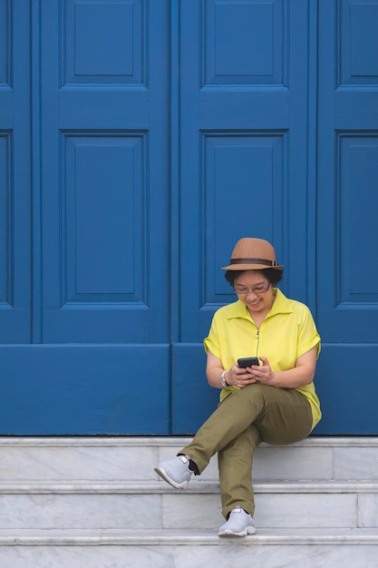 Touristin mit Smartphone auf Marmortreppe mit hölzerner Eingangstür des Retro-Gebäudes