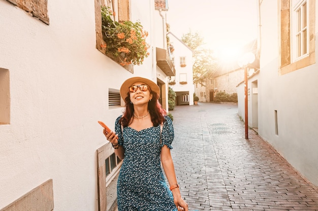 Touristin mit Smartphone läuft durch die alte europäische Stadtstraße