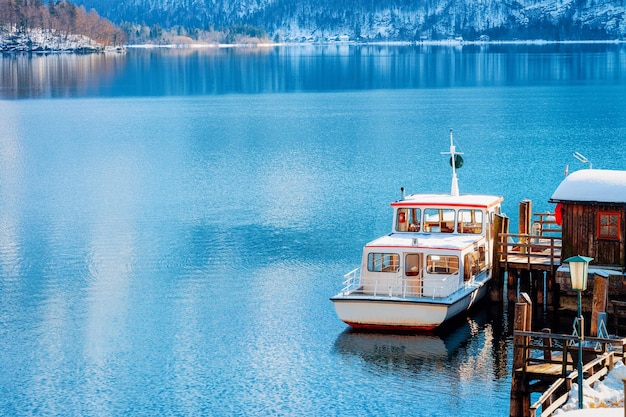 Touristische Fähre am Hallstätter See in der Nähe von Salzburg in Österreich, Europa. Winter im Salzkammergut. Reisen Sie zu Weihnachten in die österreichische Stadt mit See. Alpenland mit Schnee. Ansicht über Boot nahe Alpenbergen.