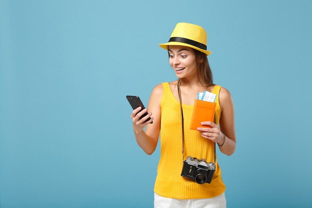 Touristische Frau des Reisenden im gelben Freizeitkleidungshut, der Kartenhandykamera auf Blau hält
