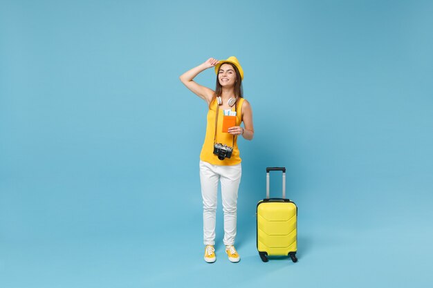Touristische Frau des Reisenden im gelben Sommerkleidungshut, der Kartentaschenkamera auf Blau hält