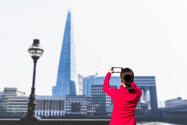 Touristische Frau, die Foto von Gebäude und von Themse mit Handy macht.