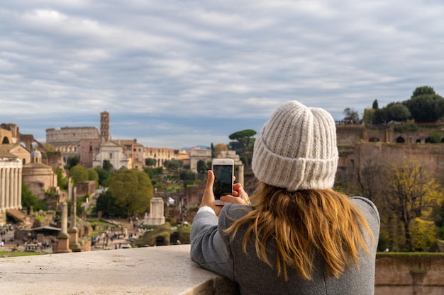 Touristische Frau, die mit ihrem Handy in der Stadt Rom Italien fotografiert