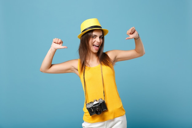 Touristische Frau in gelber Sommerkleidung und Hut mit Fotokamera auf Blau