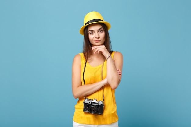 Touristische Frau in gelber Sommerkleidung und Hut mit Fotokamera auf Blau