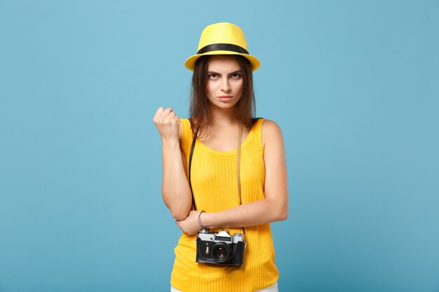 Touristische Frau in gelber Sommerkleidung und Hut mit Fotokamera auf Blau