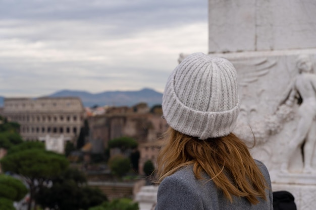 Touristische Frau mit weißer Mütze, die das römische Kolosseum bewundert