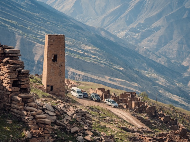 Touristische Kleinbusse vor dem alten Wahrzeichen des verlassenen Dorfes Goor in Dagestan. Russland.