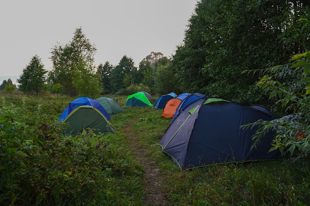 Touristische Zelte auf dem Hintergrund eines Sommerfeldes bei Sonnenaufgang. Abenteuerreisender Lebensstil. Konzept Fernweh. Aktive Wochenendferien wilde Natur im Freien.