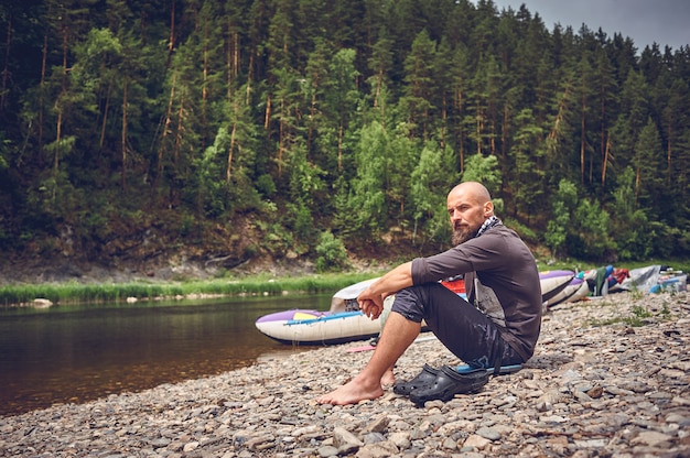 Touristischer bärtiger Mann, der auf dem Fluss ruht. Halten Sie an und entspannen Sie sich, während Sie in der Natur reisen.