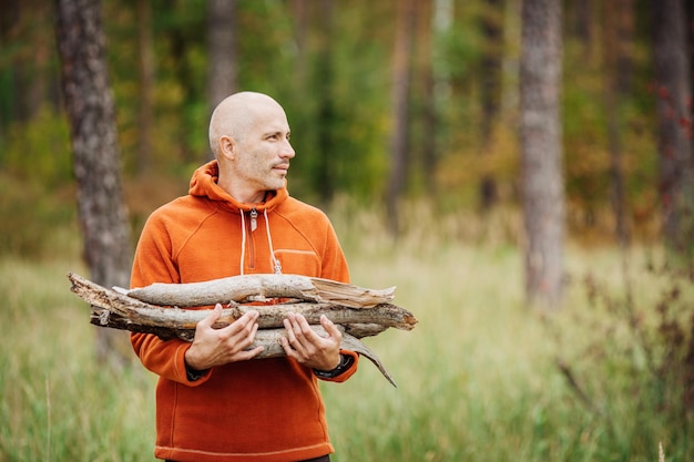 Touristischer Mann, der Holz für ein Feuer sammelt