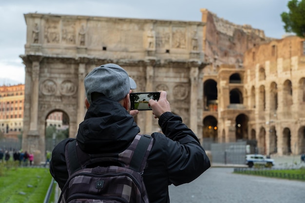 Foto touristischer mann, der mit seinem handy im kolosseum fotografiert