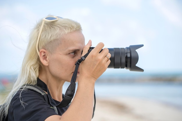 Touristischer Reisender Fotograf, der Landschaftsfotos auf Fotokamera macht Hipster-Mädchen mit Rucksack, das die wunderschöne Meereslandschaft genießt Nahaufnahme des jungen Touristen eines blonden Mädchens