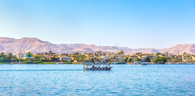 Touristisches Boot vorbei am Dorf auf dem Nil in Luxor, Ägypten