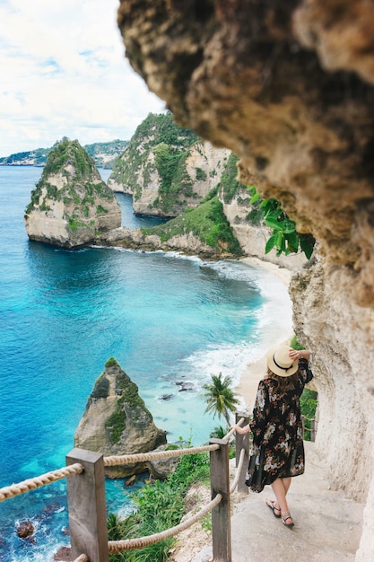 Touristisches Mädchen geht die Treppe zum malerischen Strand von Atuh auf der Insel von Nusa Penida, Bali hinunter.