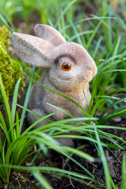 Toy Brown Bunny sitzt im grünen Busch, Nahaufnahme. Symbol des Jahres 2023