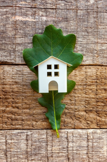 Toy House y hoja de roble verde en mesa de madera