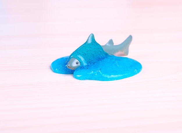 Toy Shark ertrinkt in einem blauen Schleim
