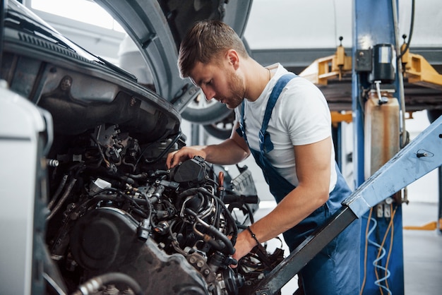 Foto trabaja para el profesional. empleado con uniforme de color azul tiene trabajo en el salón del automóvil