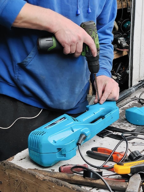 Un trabajador aficionado repara un aparato eléctrico en un lugar de trabajo improvisado Persona desconocida