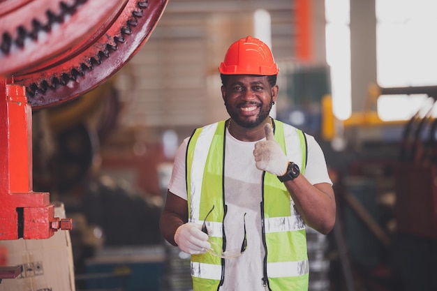 Trabajador afroamericano que trabaja en el control de máquinas pesadas en el día del trabajo de fábrica