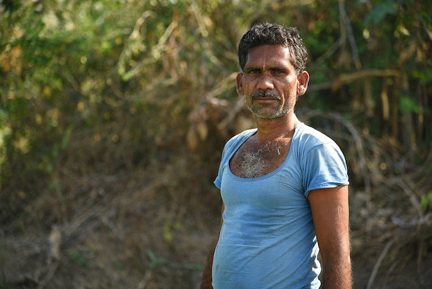 Trabajador agrícola indio no identificado plantando repollo en el campo y sosteniendo un manojo de pequeña planta de repollo en las manos en la granja orgánica.