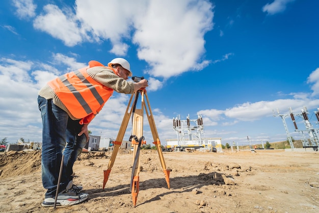 Trabajador agrimensor con equipo de teodolito en el sitio de construcción