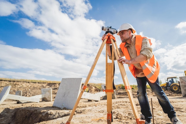 Foto trabajador agrimensor con equipo de teodolito en el sitio de construcción