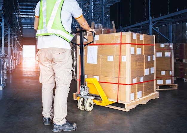 Trabajador de almacén descarga de transpaleta manual con cajas de paquetes Cadena de suministro en almacén de almacenamiento