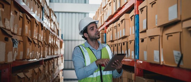 Un trabajador en el almacén usa una tableta inteligente para comprobar que el stock está en los estantes