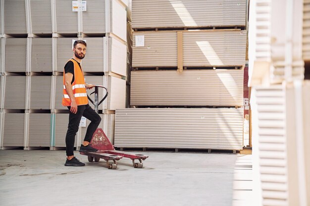 El trabajador de almacenamiento de la plataforma del carro está en el almacén con un montón de productos