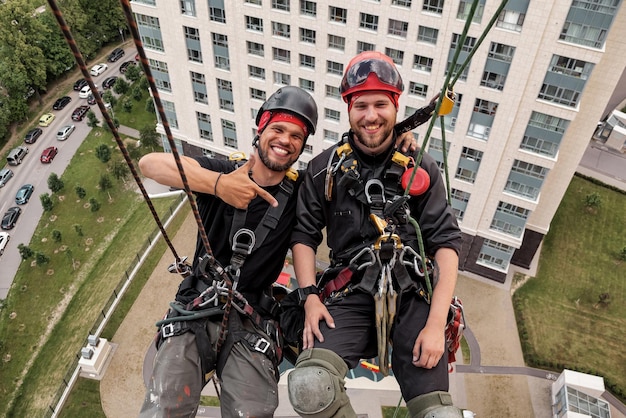 Foto trabajador de alpinismo industrial se cierne sobre edificio residencial