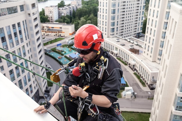 Trabajador de alpinismo industrial se cierne sobre fachada residencial