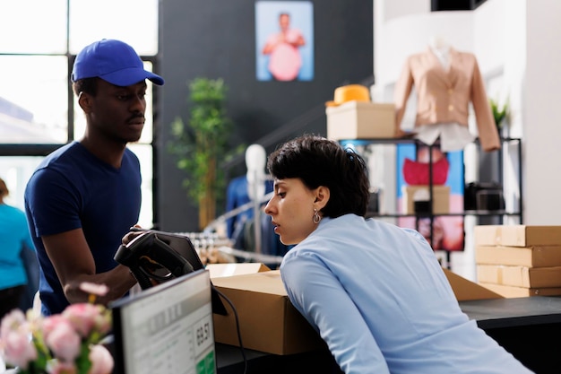 Trabajador analizando el informe de logística en una tableta, entregando paquetes al repartidor en la tienda de ropa. Empleado de pie en el mostrador, preparando pedidos en línea de los clientes en una boutique moderna