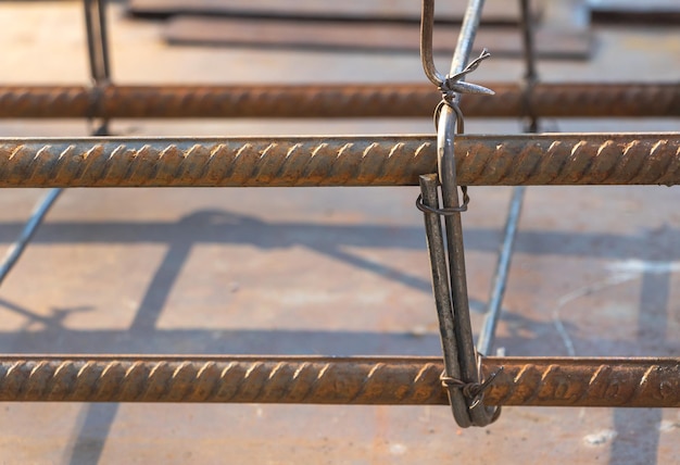 Trabajador anónimo arreglando barras de refuerzo a la luz del sol Constructor irreconocible atornillando alambre de metal con herramienta de gancho mientras arregla la barra de refuerzo a la luz del sol en el sitio de construcción