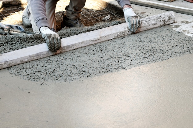 Foto trabajador aplanando piso de concreto