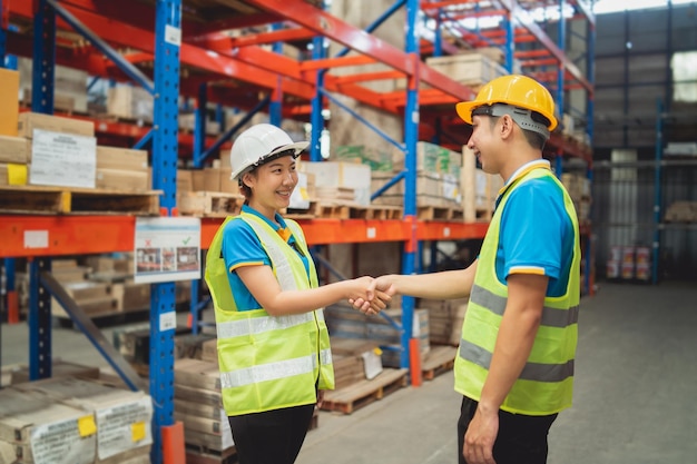 El trabajador asiático del almacén industrial en el apretón de manos de la suite de seguridad celebra el compromiso exitoso o del acuerdo Cadena de suministro de logística y negocio de almacén Unidad de trabajo en equipo bajo el concepto de vista