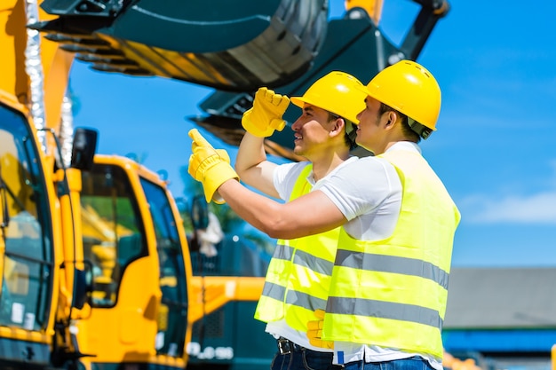 Trabajador asiático en maquinaria de construcción del sitio de construcción