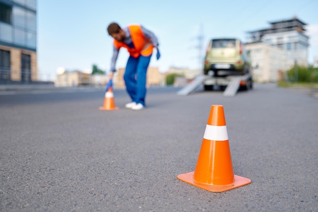 Trabajador de asistencia en carretera poniendo conos cerca del evacuador