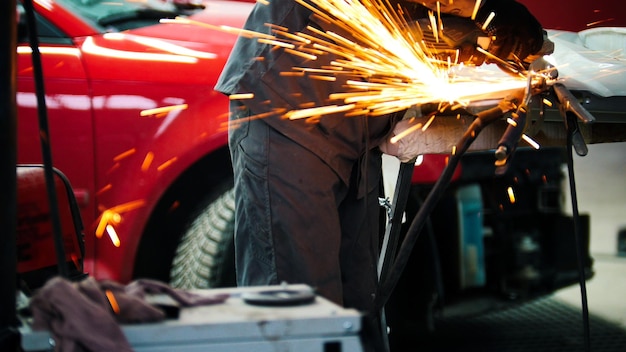 Trabajador de auto servicio de coche pulido de construcción de metal con una sierra circular